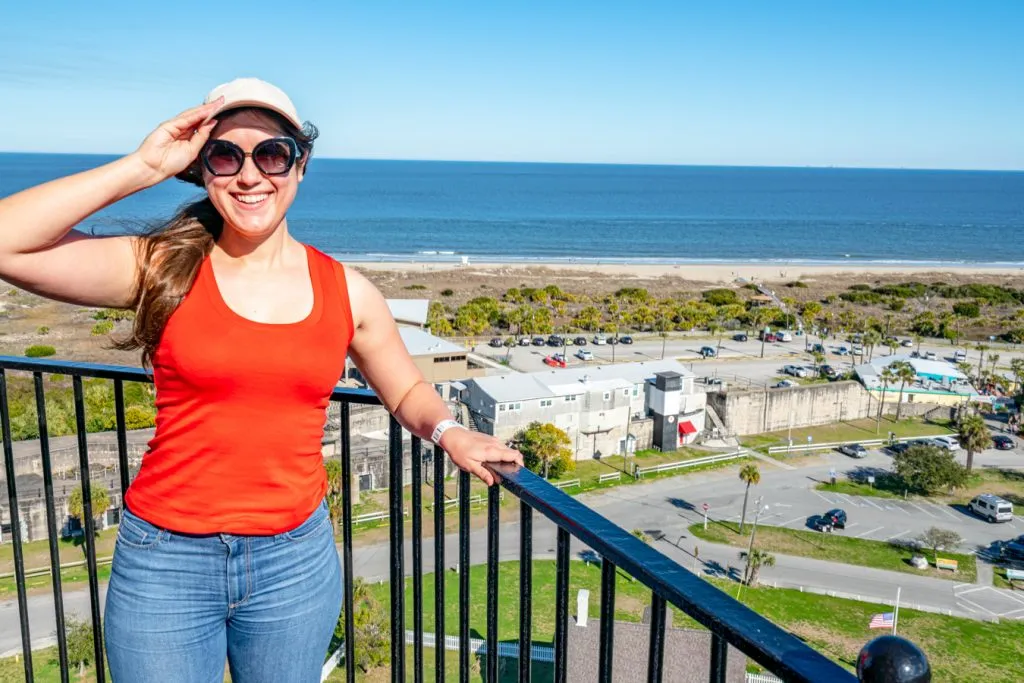 kate storm in an orange tanktop overlooking the beach of tybee island from the top of the tybee lighthouse, one of the best day trips from savannah ga