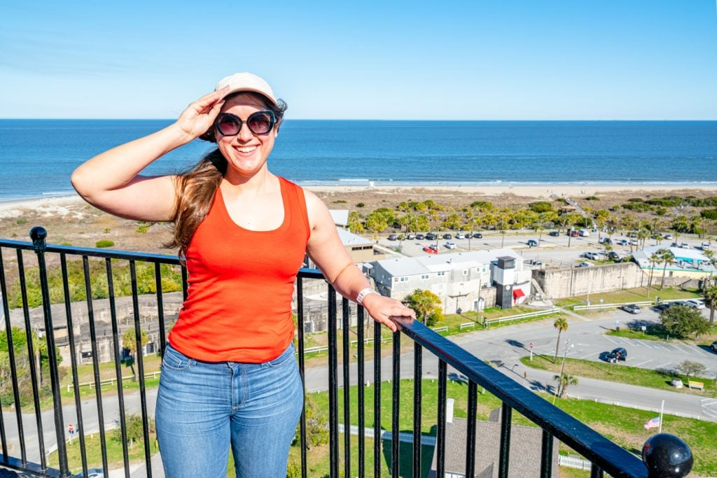 kate storm in an orange tanktop overlooking the beach of tybee island from the top of the tybee lighthouse, one of the best day trips from savannah ga