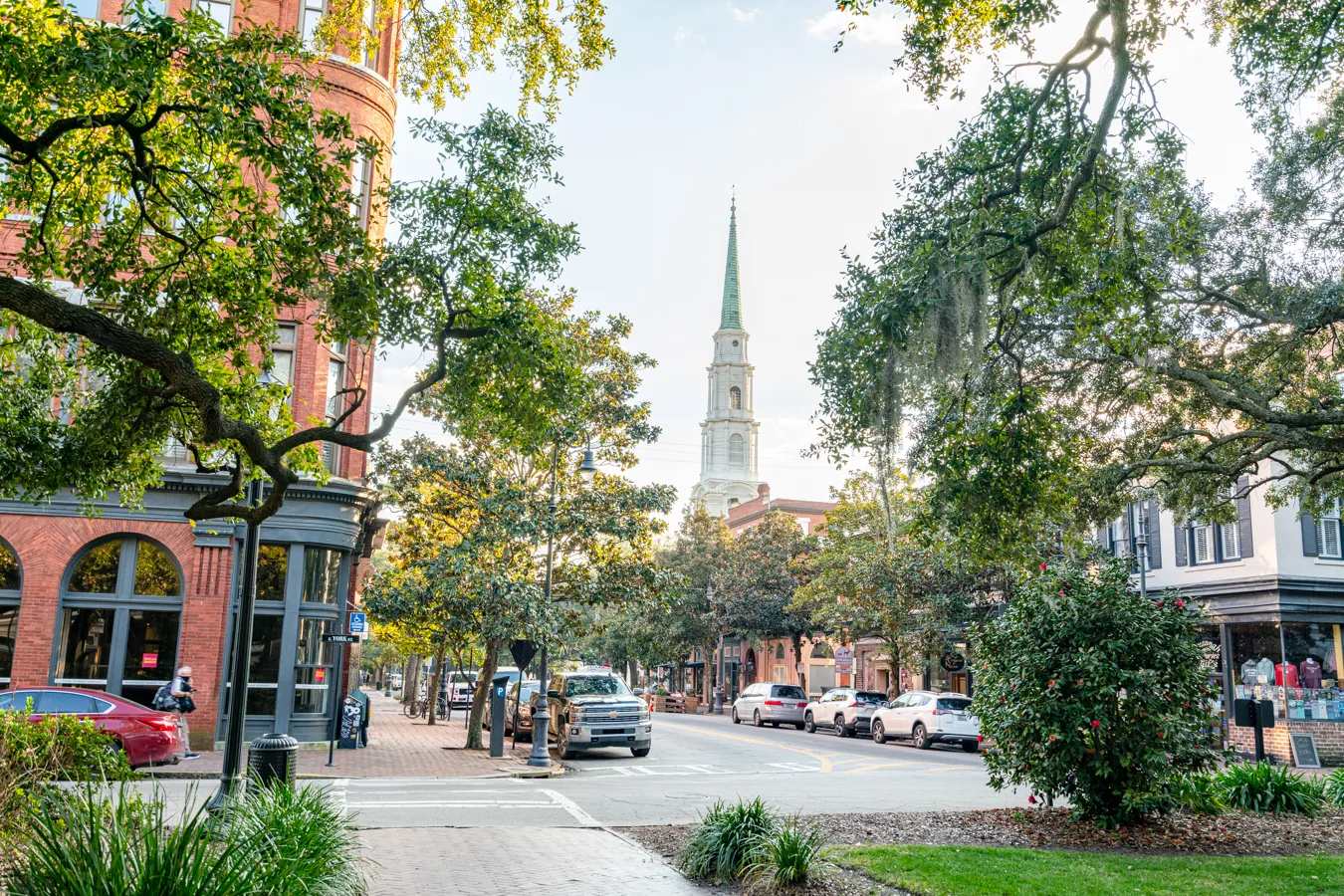 view of one of the prettiest streets in savannah ga from a square with steeple in the background