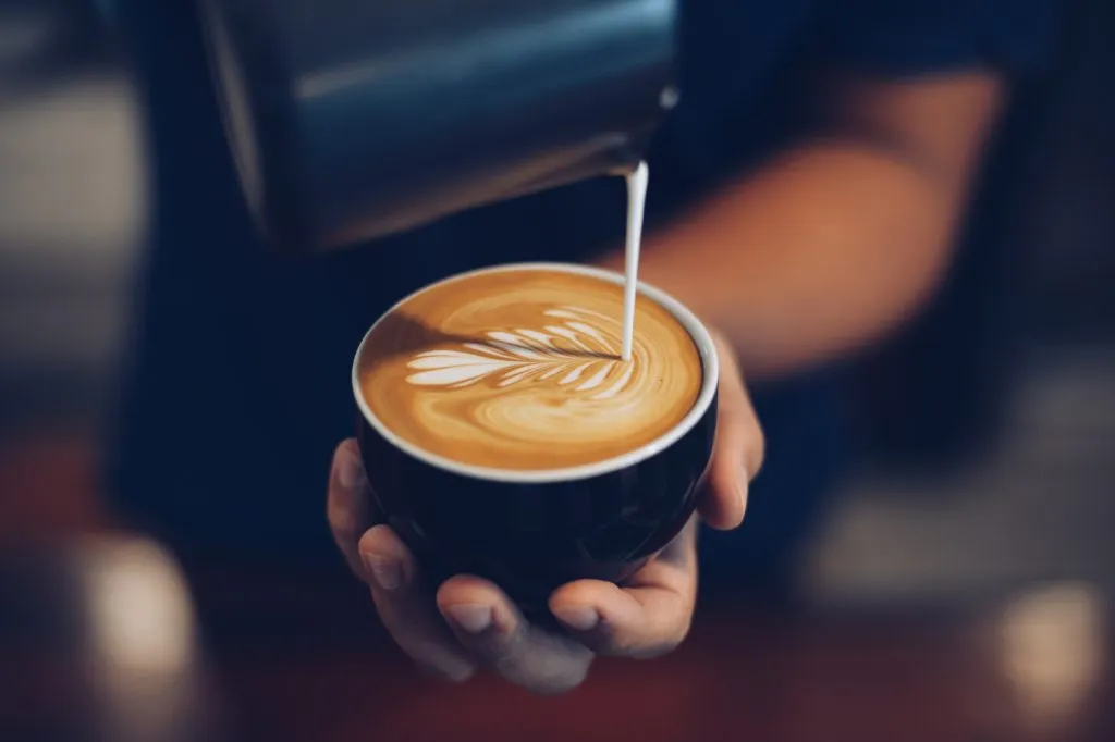 milk being poured into a latte by a barista
