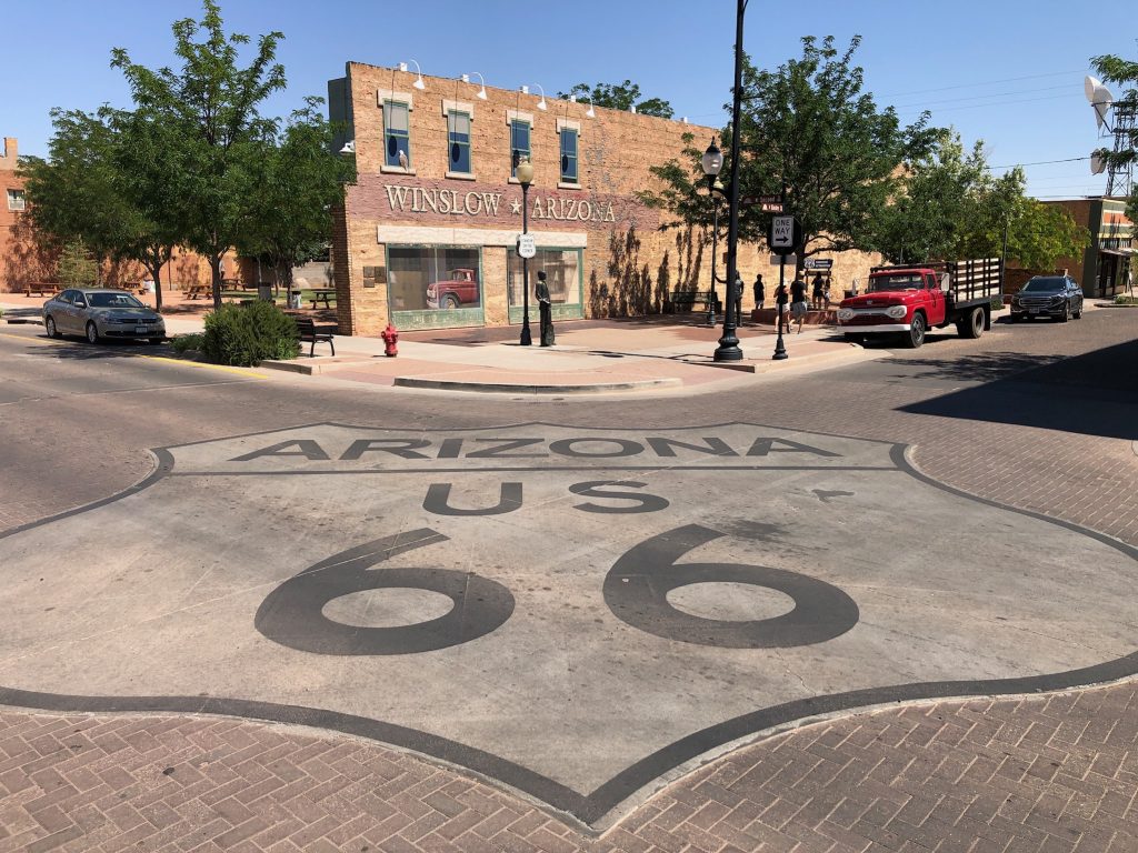 photo of standin on the corner park in winslow arizona with a route 66 sign in foreground painted on the ground