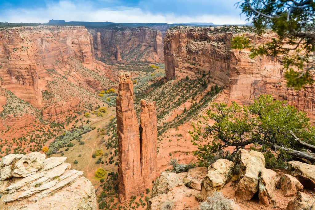 view overlooking canyon de chelly with a sandstone pillar in the center foreground
