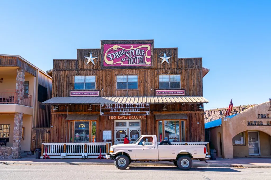 fort davis drugstore hotel in west texas with a pink truck parked in front of it, part of one of the best road trips in us southwest