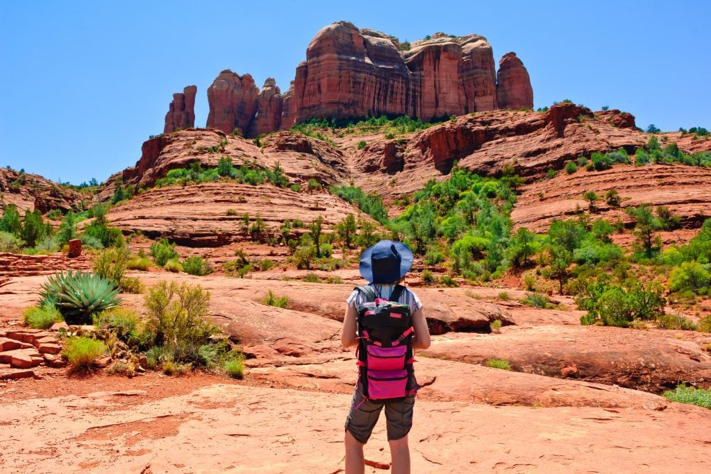 woman in a red backpack hiking in sedona on a southwest road trip of a lifetime