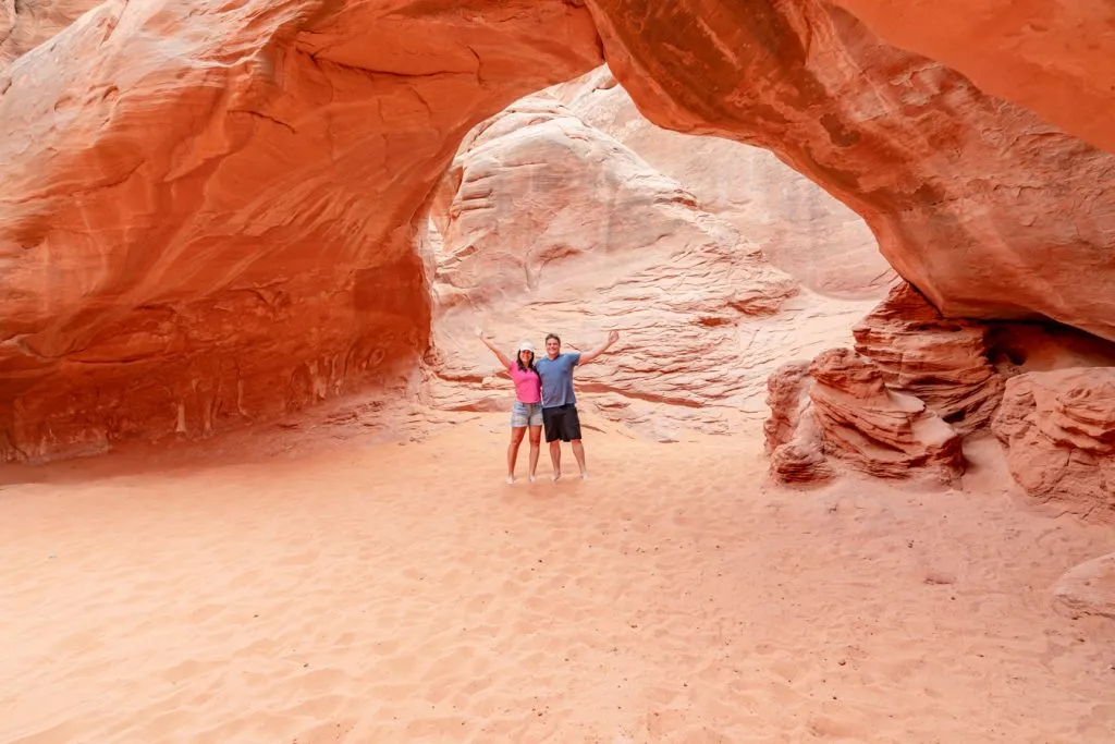 kate storm and jeremy storm under an arch in arches national park