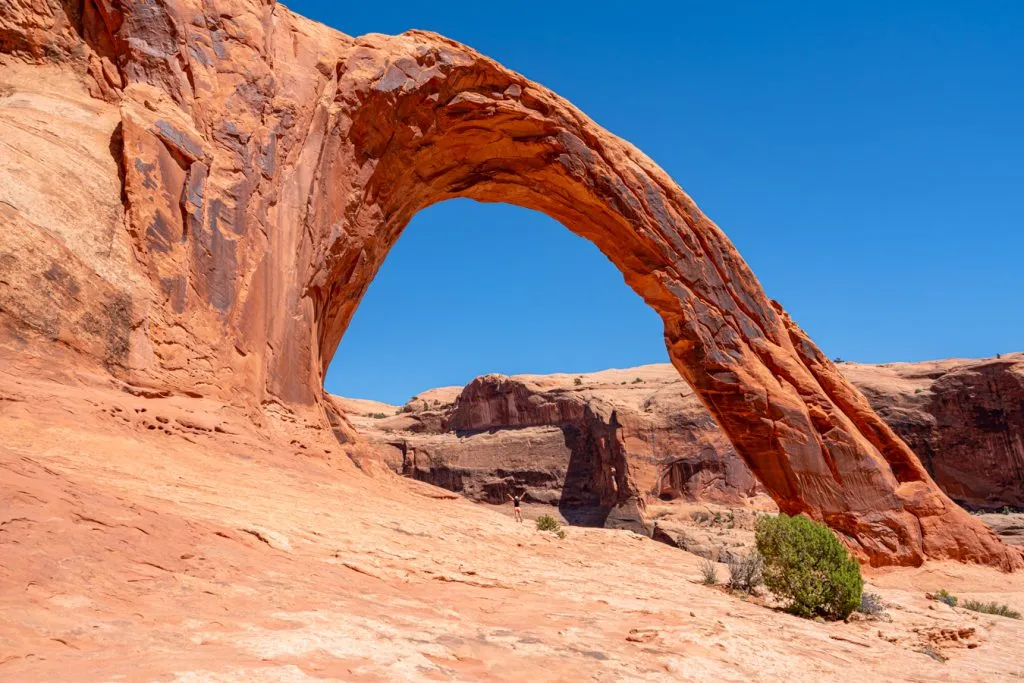 kate storm standing under corona arch in moab ut