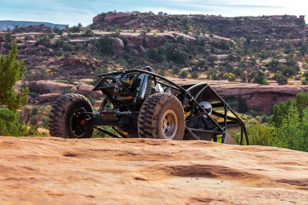 a black 4x4 climbing up a rock hill near moab. off-roading is one of the top moab activities