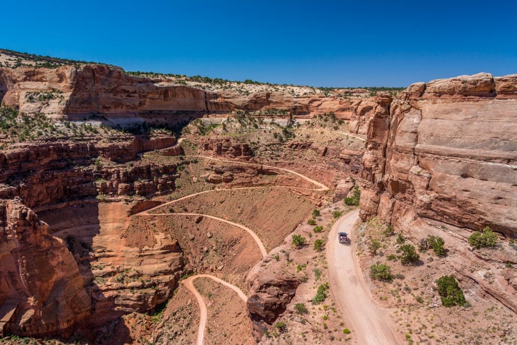 view of a 4x4 from above driving along shafer trail in canyonlands national park