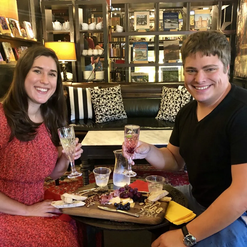 kate storm and jeremy storm during a long weekend asheville getaway in battery park book exchange and champagne bar with champagne flutes