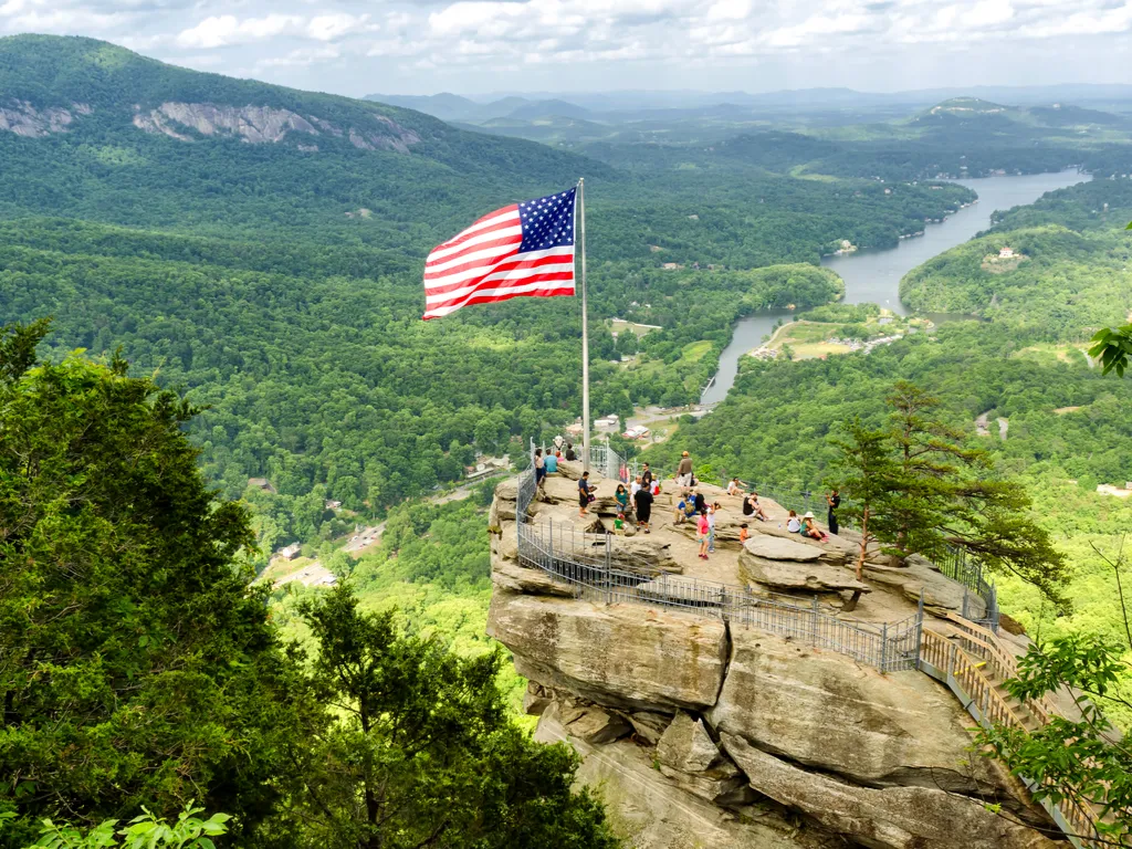 chimney rock nc with an american flag flying from it, one of the best things to see during a long weekend in asheville itinerary