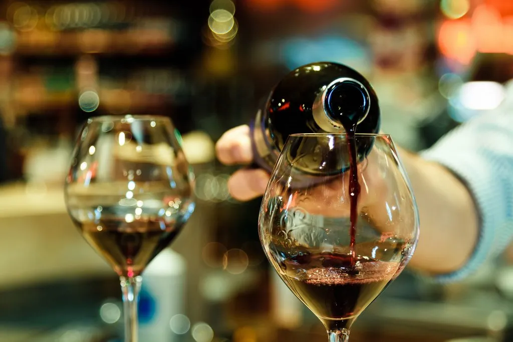 two glasses of red wine being poured