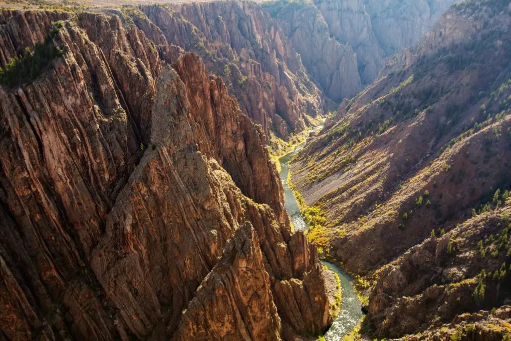 black canyon of the gunnison as seen from above with river to the right, one of the bucket list colorado places to visit