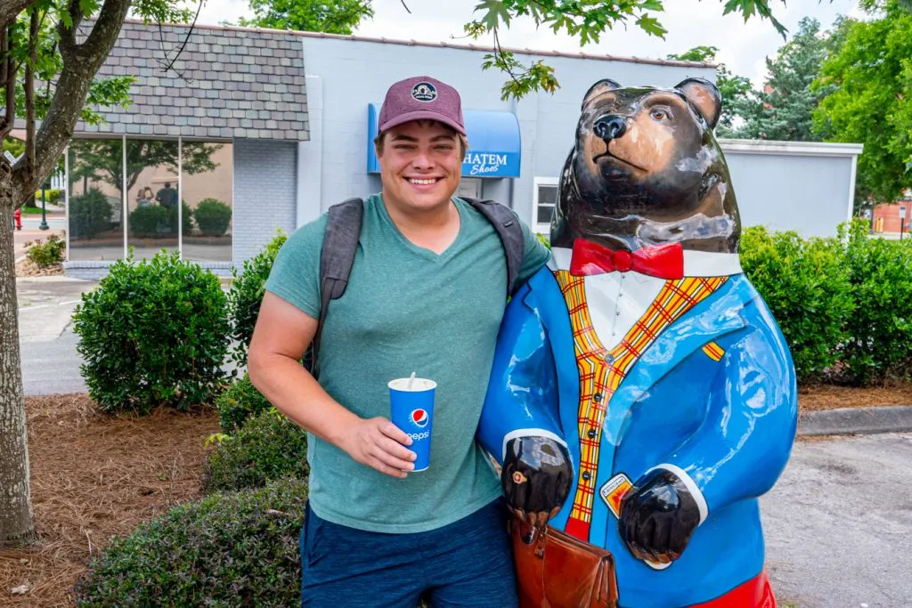jeremy storm posing with a bear statue, one of the fun attractions in new bern north carolina