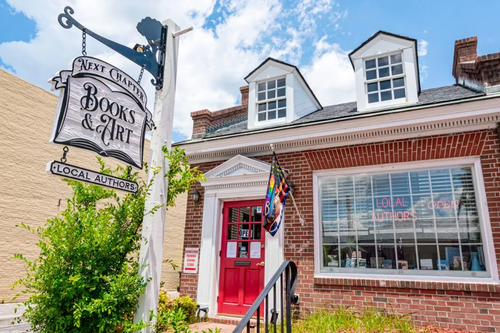 front facade of next chapter books with hanging sign and red front door