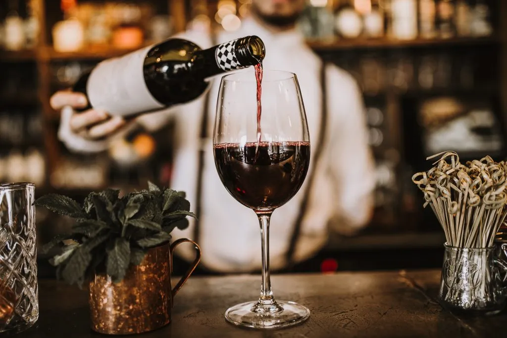 sommelier pouring a glass of red wine at a wine tasting