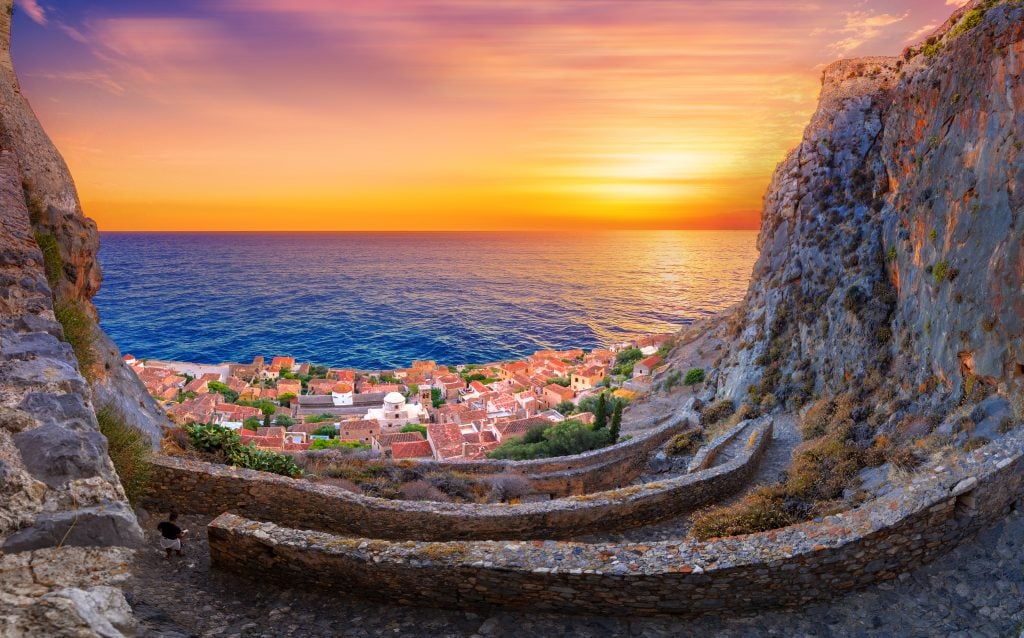 sunset over Monemvasia greece with winding stone road in the foreground