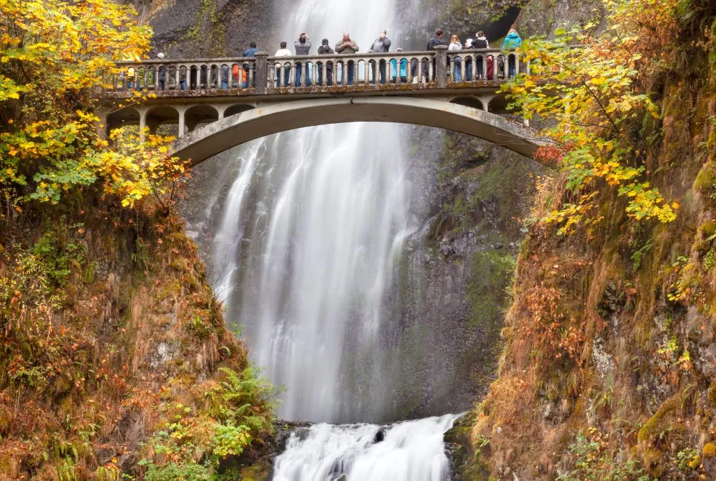 travelers admiring multnomah falls from historic bridge, best places to visit in usa in november