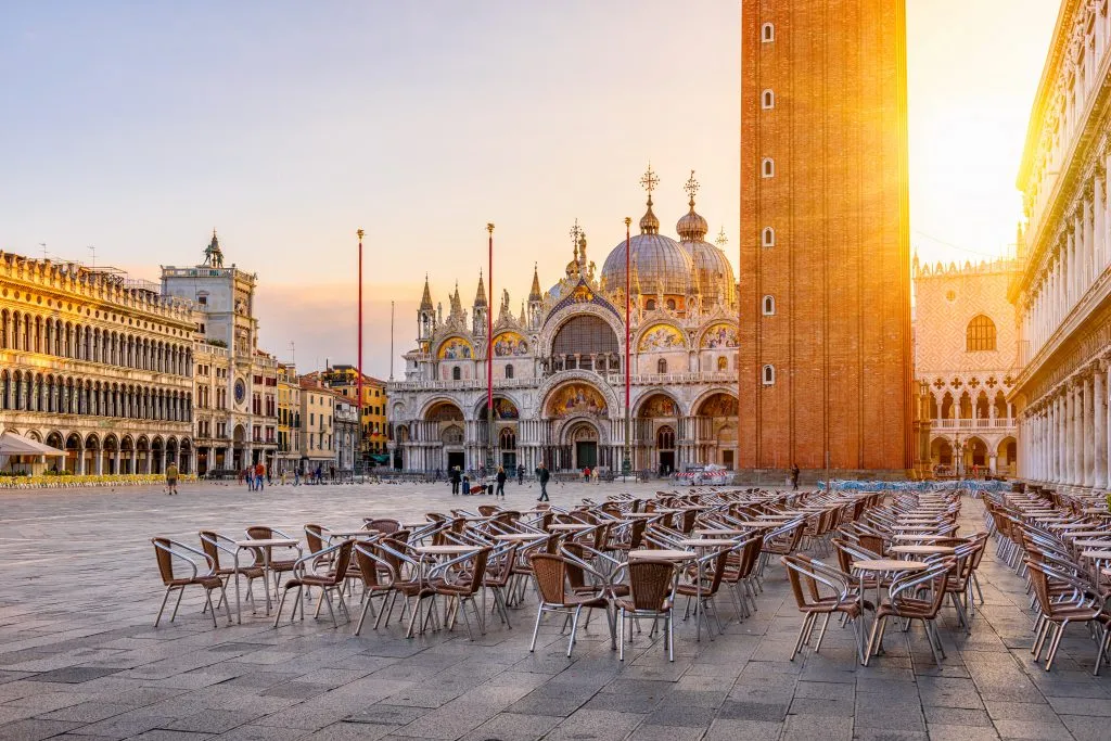 view of venice st marks square at dawn with cafe tables set out for the day