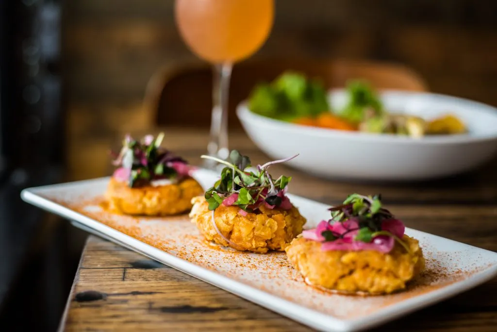 three crab cakes served on a white rectangular plate