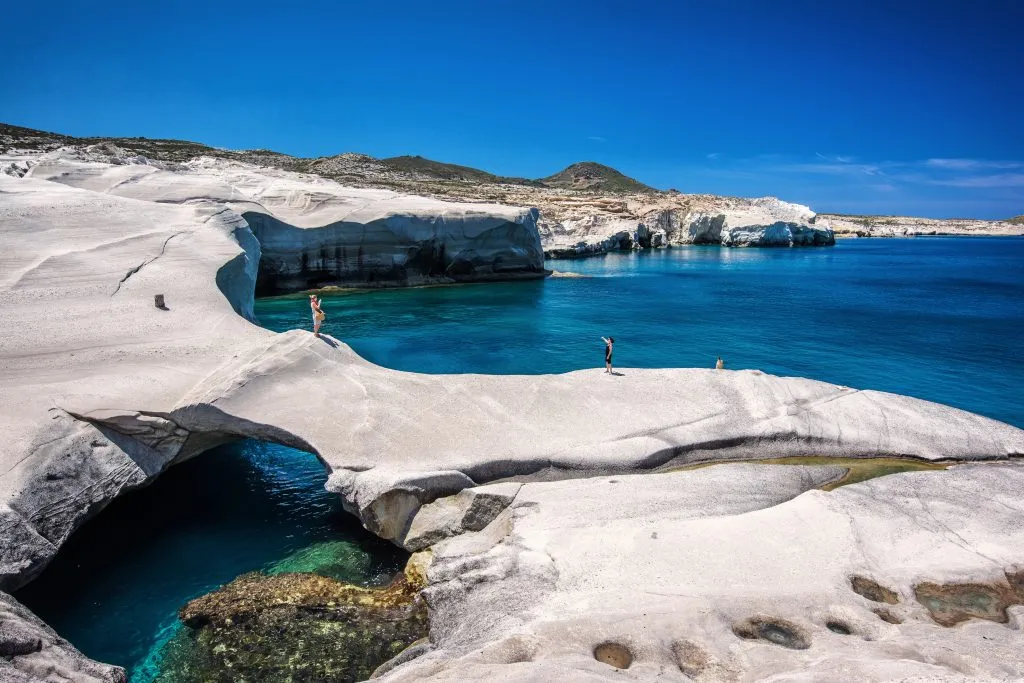 people walking over rock formations at Serakiniko Beach, one of the best places to visit in greece in 7 days itinerary