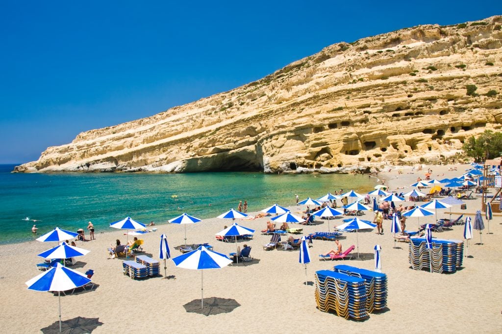 view of a crete beach with blue and white umbrellas on it