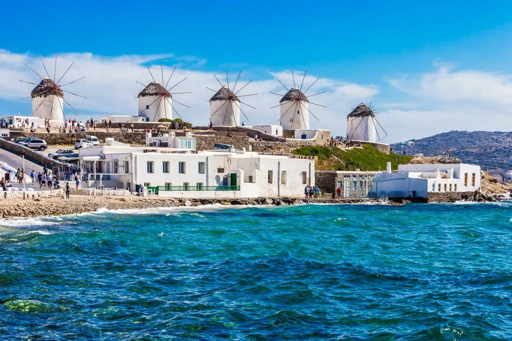 mykonos windmills as seen from the water, a popular stop on a greece island hopping itinerary