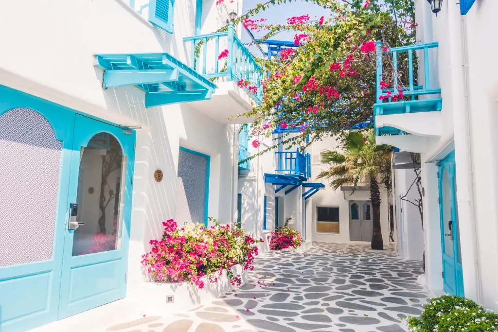 small street in a blue and white village greece with pink flowers