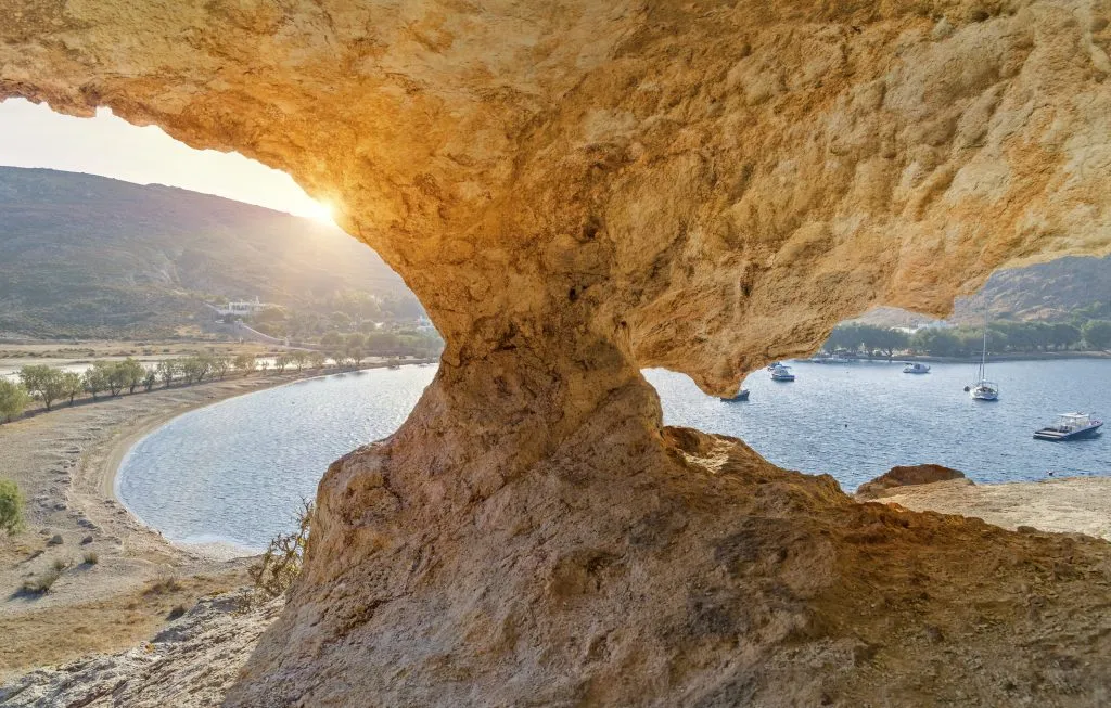 beach in patmos at sunset as seen from inside a rock cave above the beach