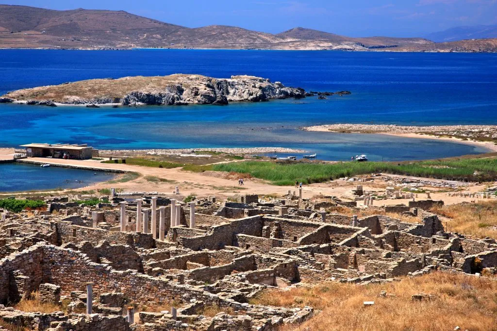 view of delos island greece from above with ruins in the foreground and sea in the background, one of the best stops on a itinerary for greece 7 days