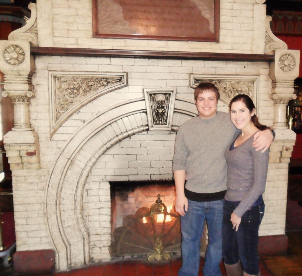 kate storm and jeremy storm in front of a fireplace in crescent hotel eureka springs arkansas