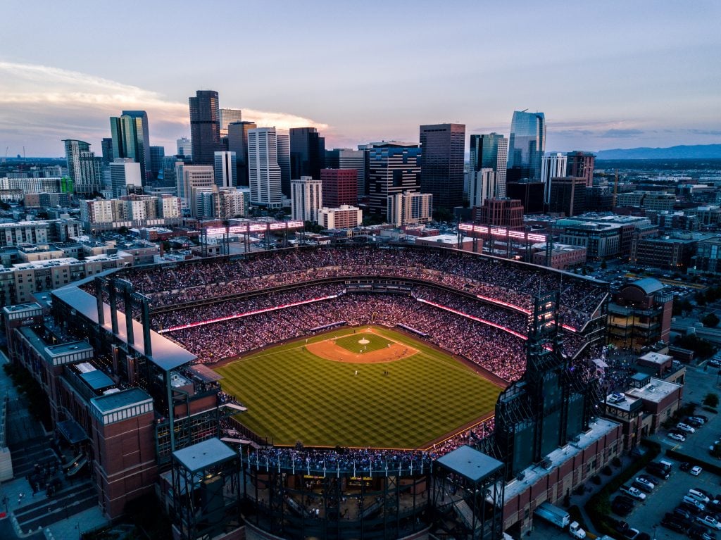 aerial view of a denver rockies game at night with the skyline in the background