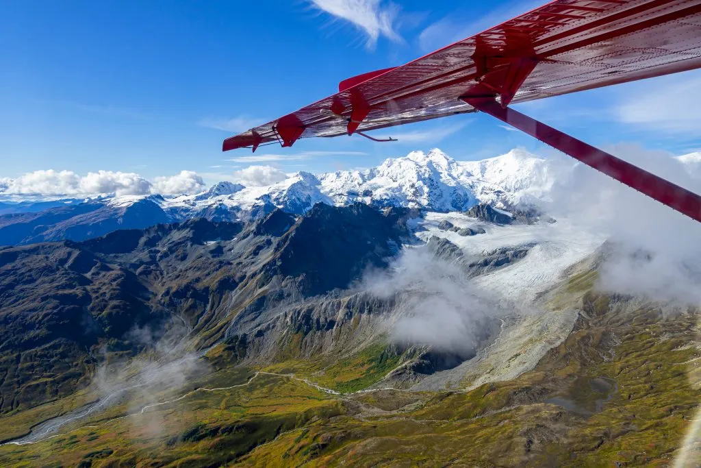 view of snowcapped mountains in alaska from a small red plane on a flightseeing tour, one of the top things to do in usa