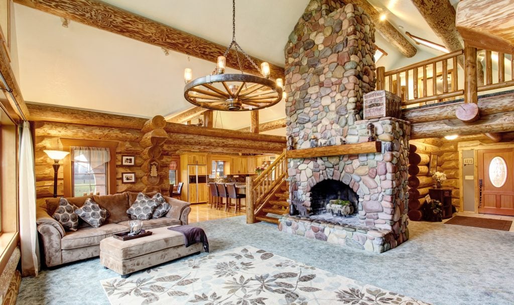 interior of a luxurious log cabin with a stone fireplace in the center