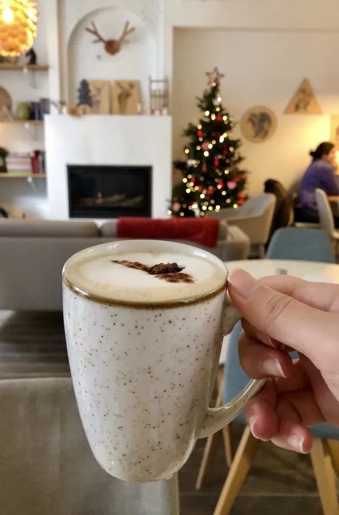 kate storm holding a cup of belgian hot chocolate in a cafe in belgium in winter