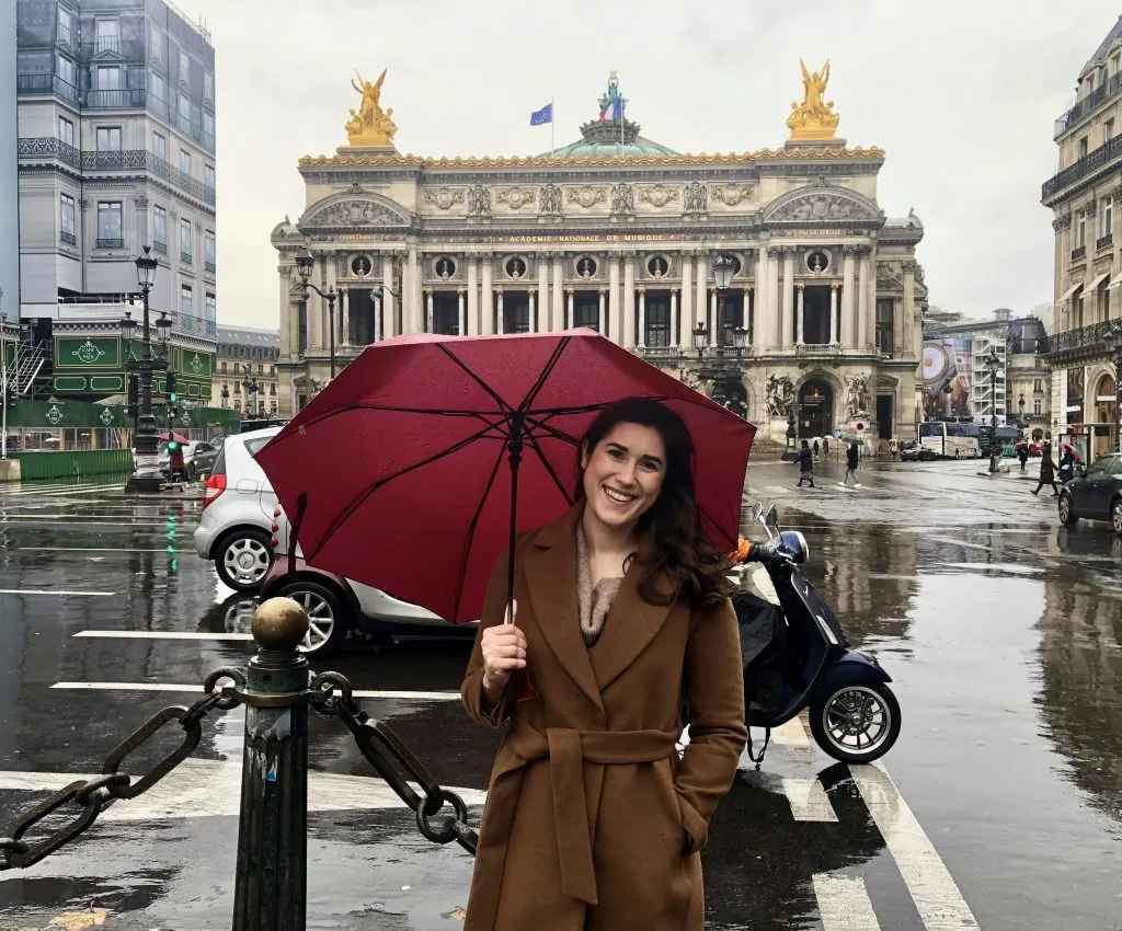 kate storm with a pink umbrella in front of the opera house in paris in the rain