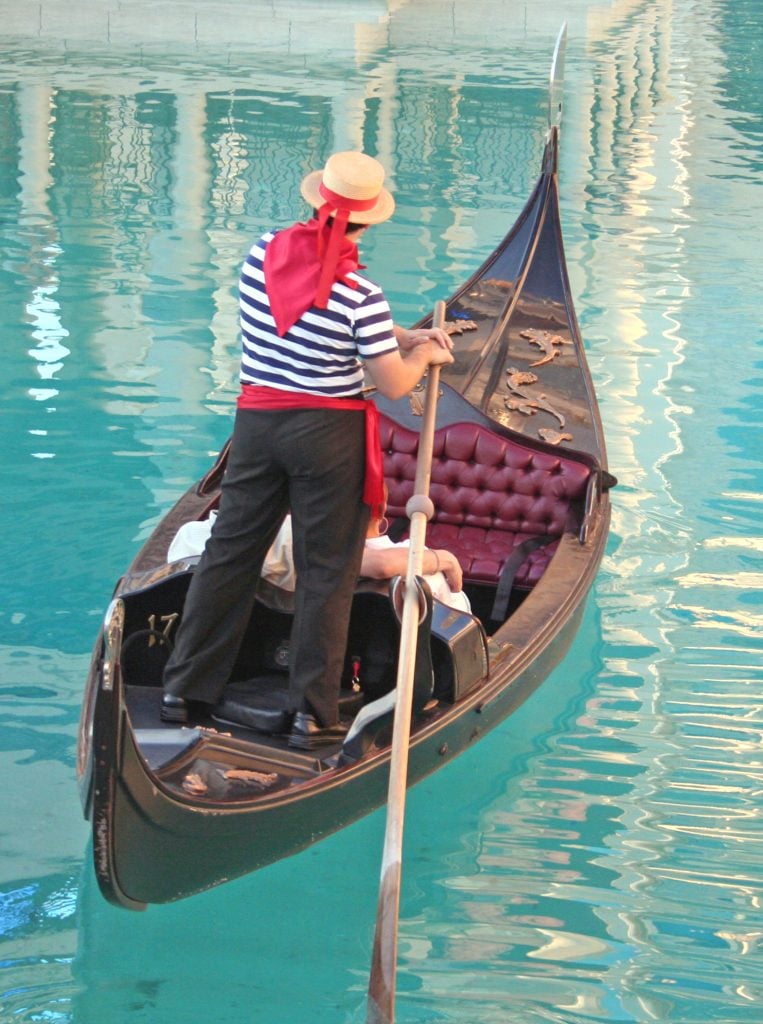 gondolier steering a gondola in the canal of venetian las vegas nevada