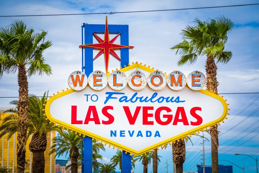 close up of welcome to las vegas sign framed by palm trees