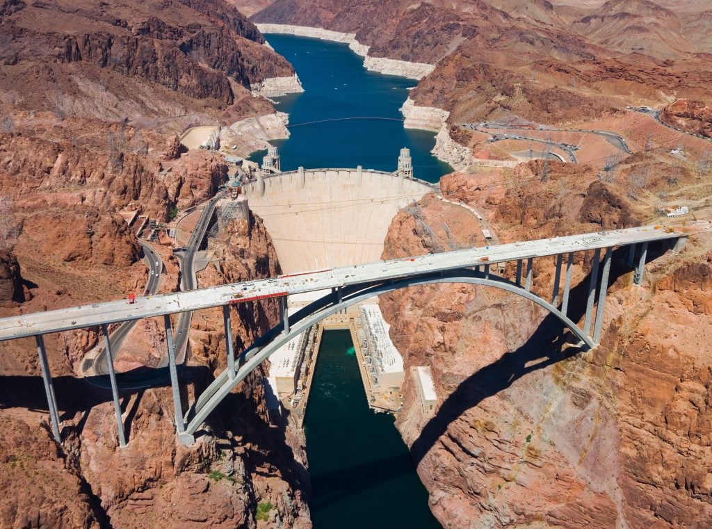 aerial view of the hoover dam with bridge in the foreground, one of the best day trips during a long weekend in vegas itinerary