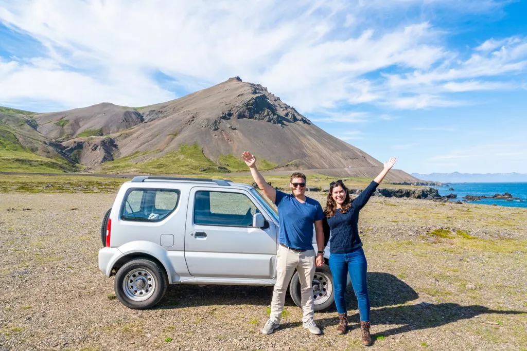 kate storm and jeremy storm posing in front of a rental car iceland ring road trip