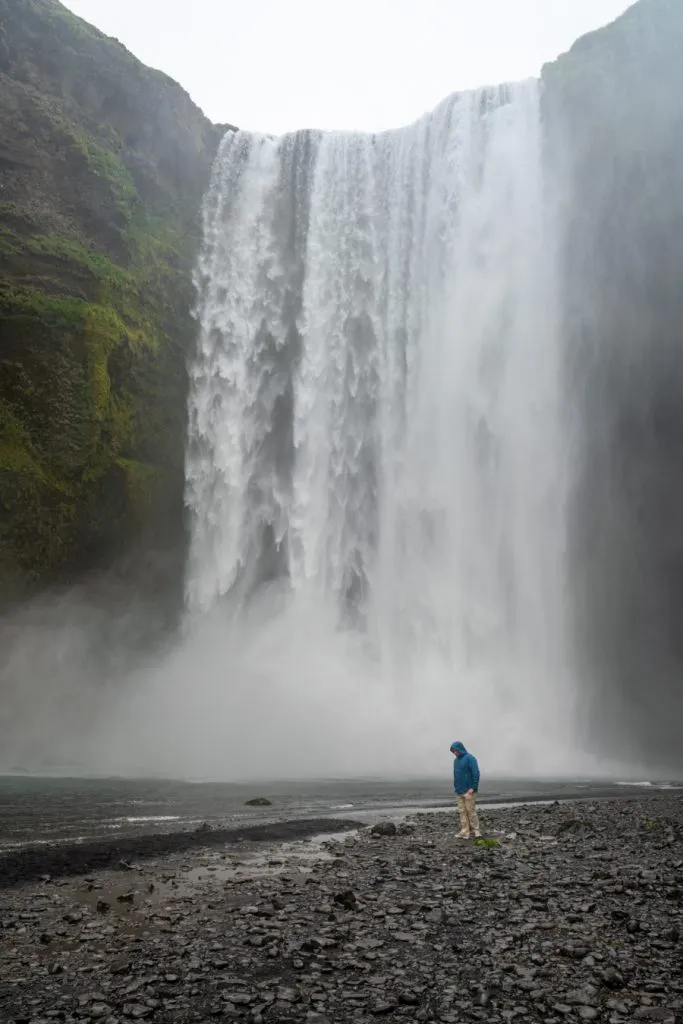 jeremy storm in front of skogafoss waterfall wearing blue jacket