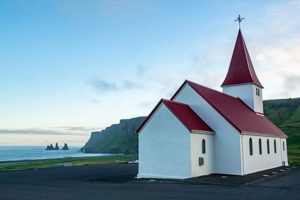 famous red and white church in vik iceland at sunset