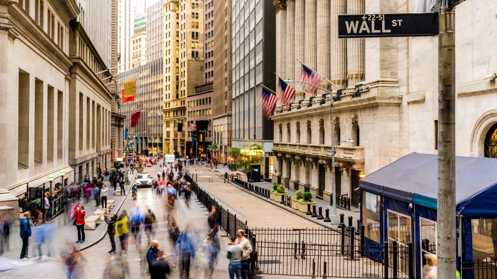 long street of wall street new york city on a cloudy day with people walking past the stock exchange