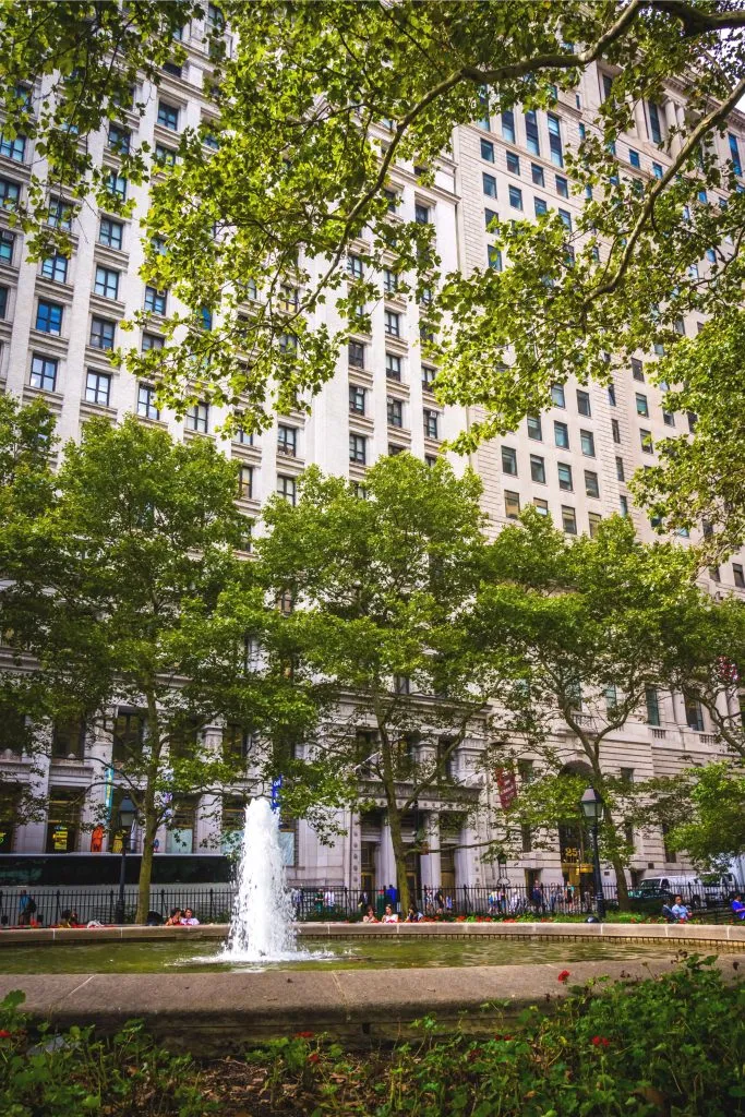 fountain in bowling green park nyc with skyscrapers in the background