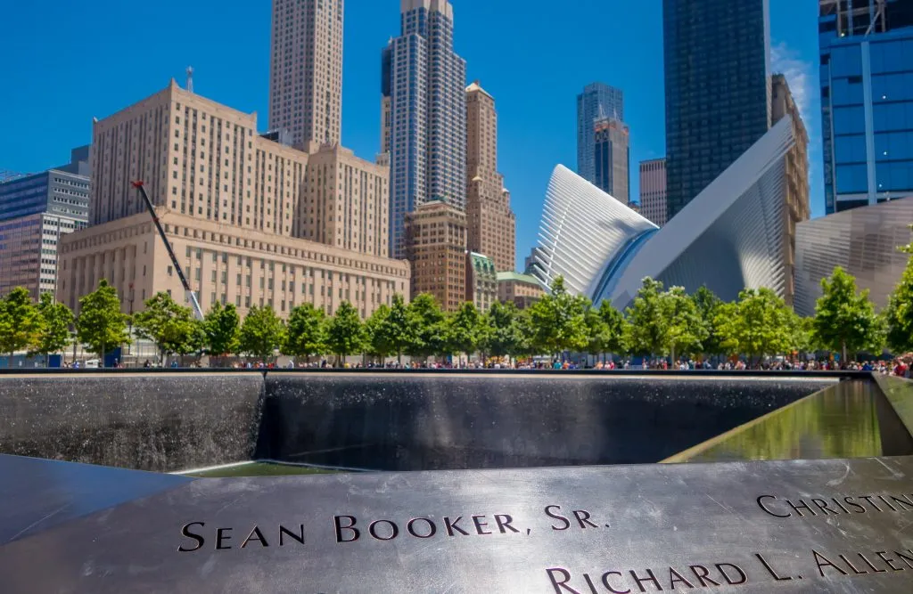 view of 9/11 memorial in financial district new york city with pool in the foreground and oculus in the background