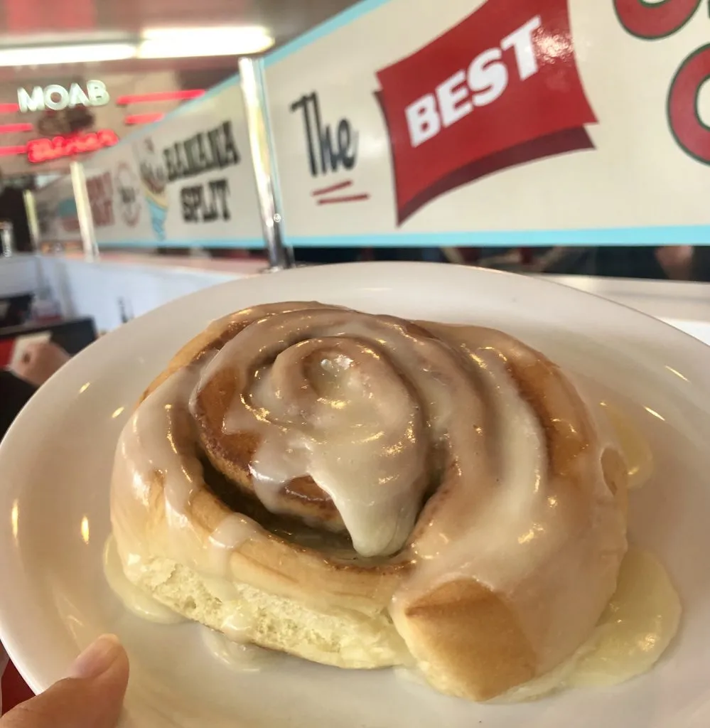 large cinnamon roll being held up in moab diner, one of the best restaurants moab utah