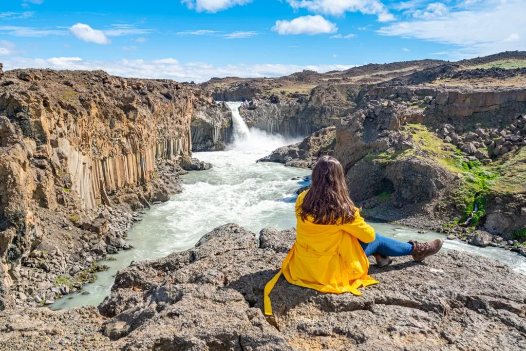 kate storm sitting in front of aldeyjarfoss iceland waterfalls