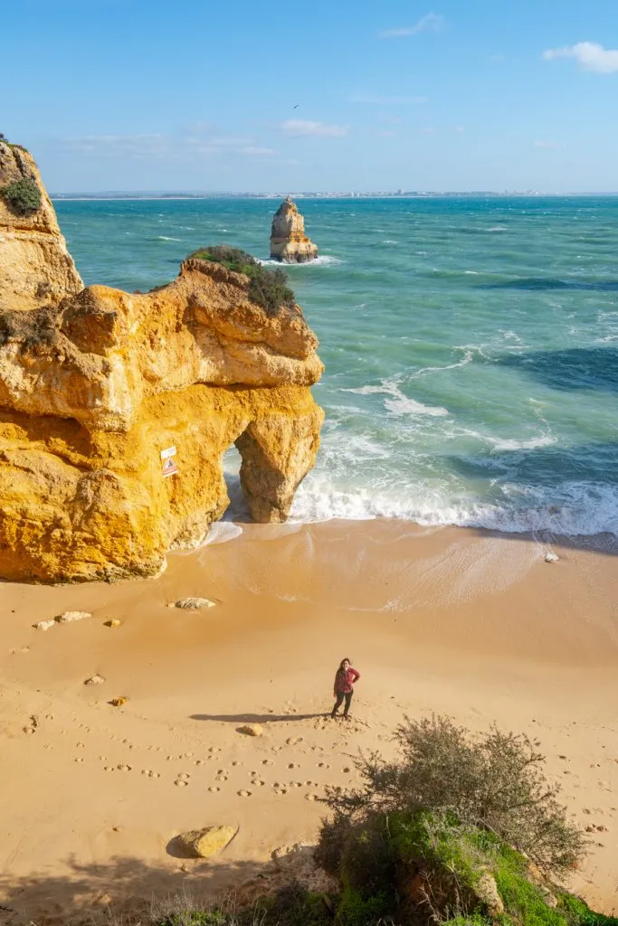 kate storm standing on praia do camilo in the algarve in january