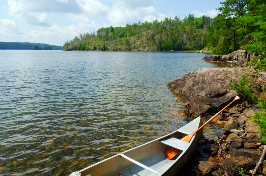 canoe pulled up to the shore in minnesota boundary waters, one of the most underrated vacations in usa