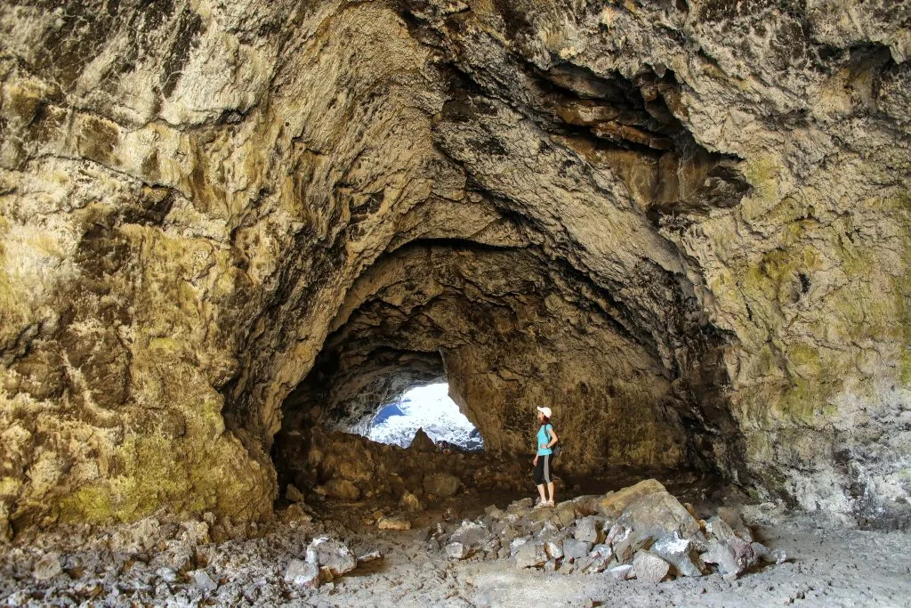 indian tunnel cave with a hiker in front of it at craters of the moon national monument idaho