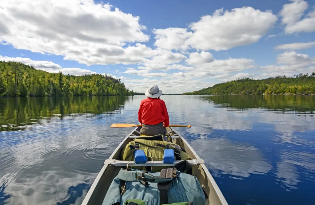 person in red sweatshirt at the front of a canoe on minnesota boundary waters